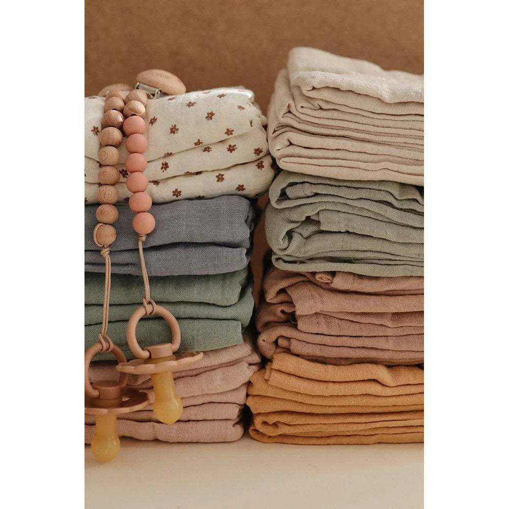 Gestapelte, gefaltete Babybekleidung und Accessoires in sanften Erdtönen