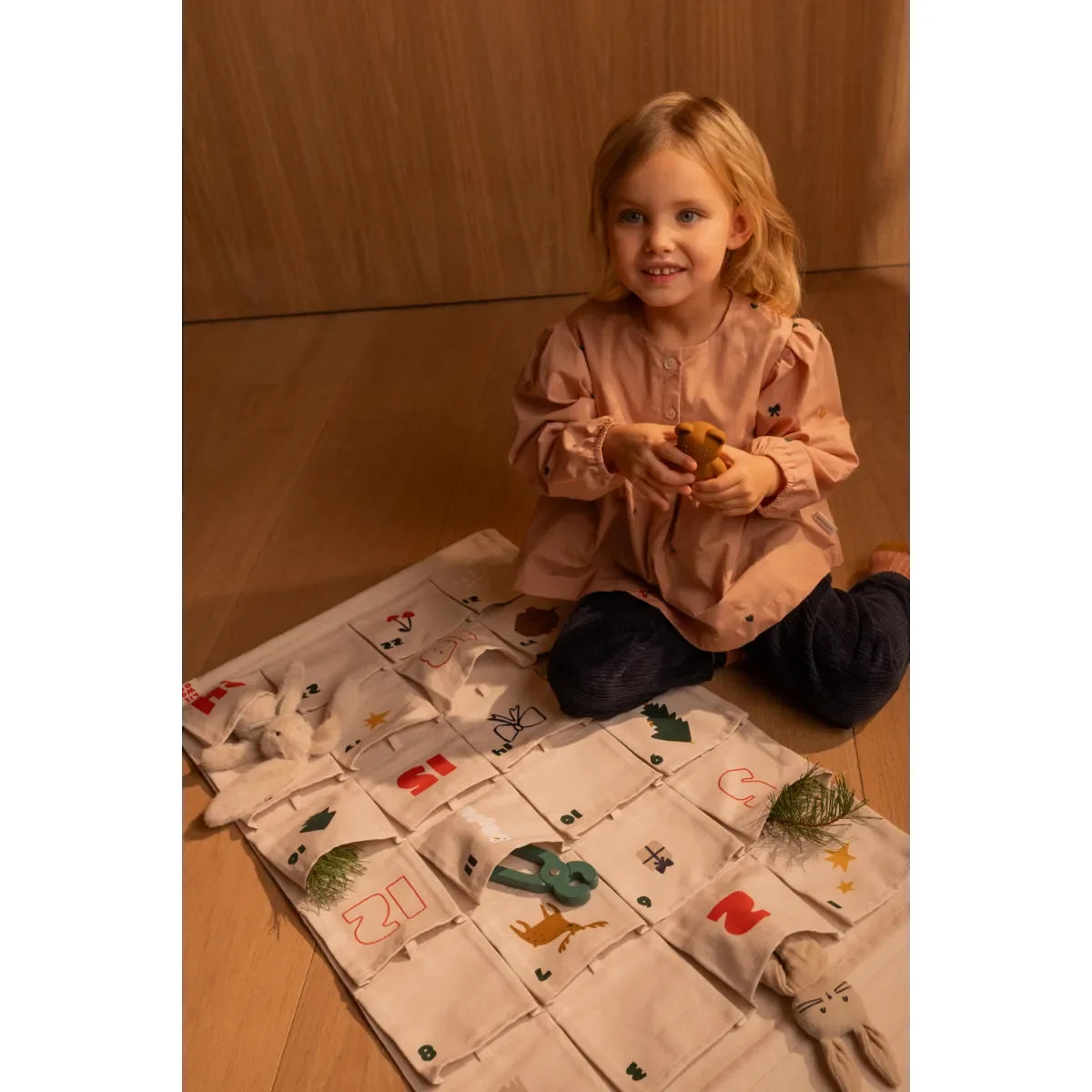 Lächelndes junges Mädchen hält kleines Objekt neben Adventskalender Holiday Sandy