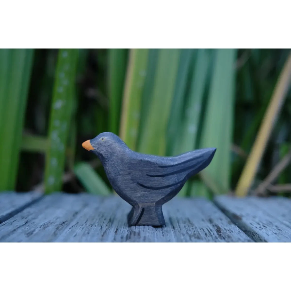 Schwarze Amsel-Figur aus Holz oder Keramik mit orangem Schnabel und Füßen