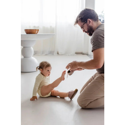 Ein Mann interagiert mit einem kleinen Kind auf dem Boden im Baby Body Langarm natur