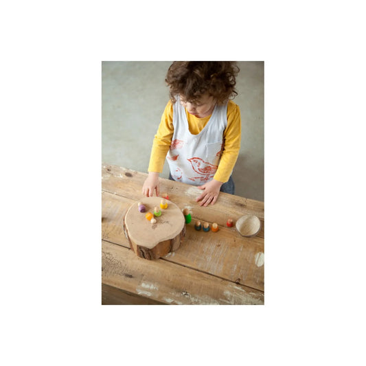 Holzstumpf-Tisch mit bunten Perlen und Schälchen für Baby Nins Spiel