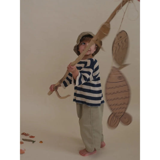 Kind mit Angelrute trägt Ballonhosen von Seasalt am Wasser