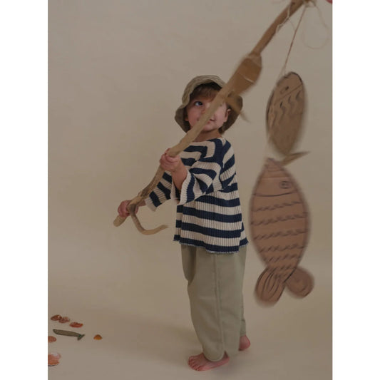 Kind mit Angelrute trägt Ballonhosen von Seasalt am Wasser