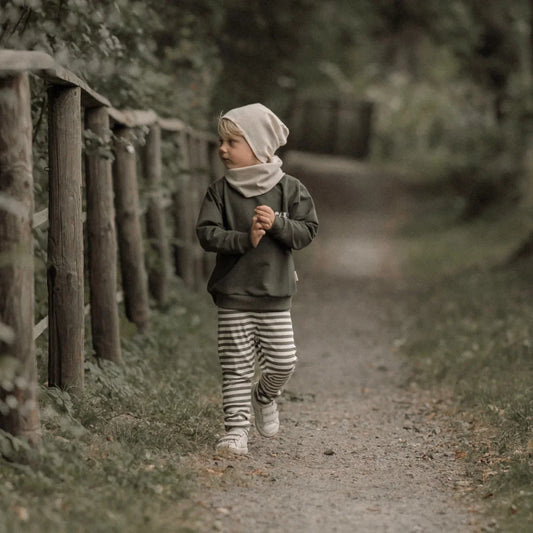Kind eines Kindes in grüner Langarmshirt, gestreiften Hosen, Ecru Beanie und Halswärmer