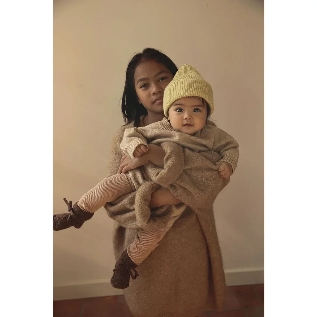 Frau hält ein Kind mit einer hellgelben Mütze namens Beanie Fonzie