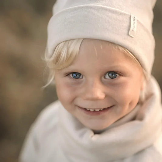 Lächelndes Kind mit weißem Hut und Schal im Beanie Rib Strick in Beige