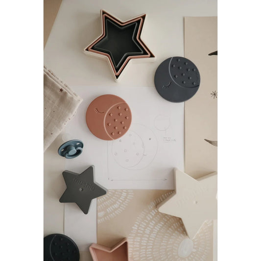 Dekorative Formen wie Sterne, Kreise und Monde in verschiedenen Farben und Materialien