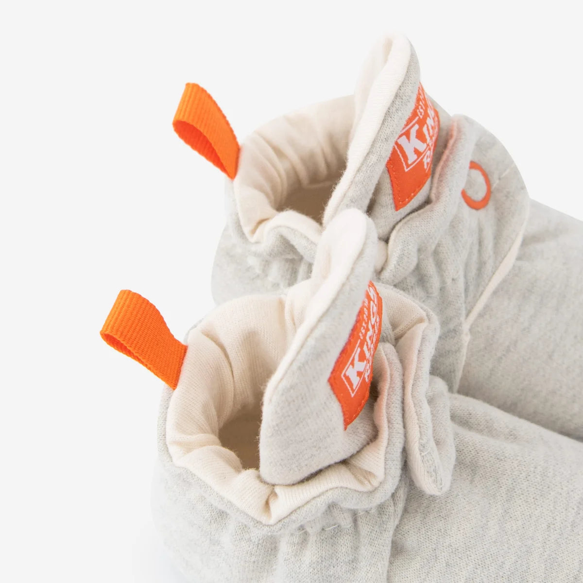 Graue strick babybooties mit orangefarbenen stofflaschen und weichem beige innenfutter nachhaltige babykleidung schweiz