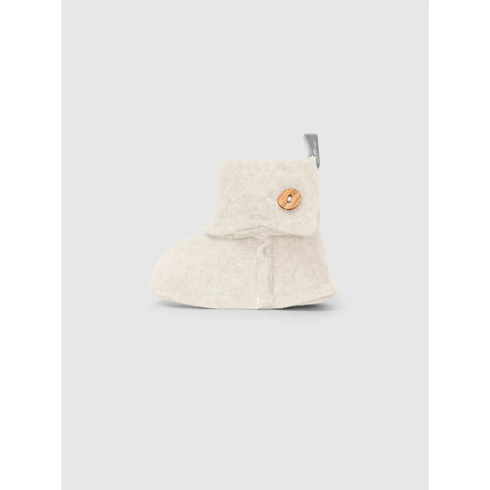 Ein cremefarbener Babybootie mit Holzknopf aus Fleece im Produkt Booties in Fleece Sand