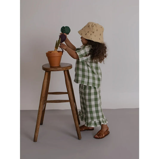 Kleines Kind in Dill-Gingham-Boxy-T-Shirt gießt Blumentopf-Kaktus