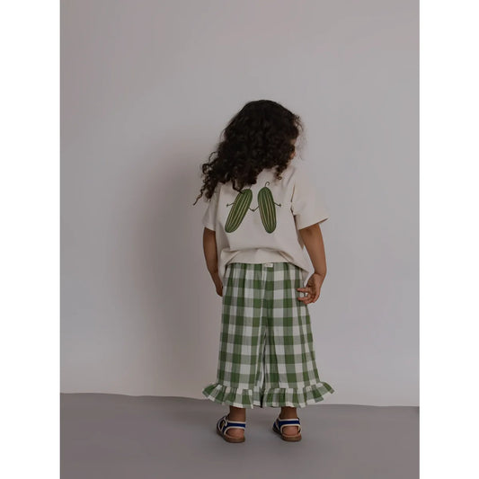 Rückseite: Kind in Boxy T-Shirt Friends Of the Garden mit Gurken-Print, Gingham-Hose