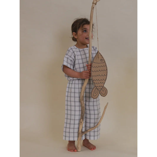 Kind hält eine Angel mit einem Pappfisch in Check Weite Hose | Marine Schachbrett