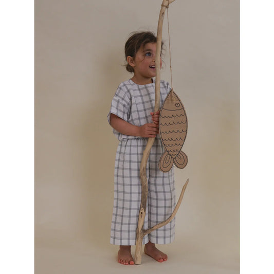 Kind hält eine Angel mit einem Pappfisch in Check Weite Hose | Marine Schachbrett