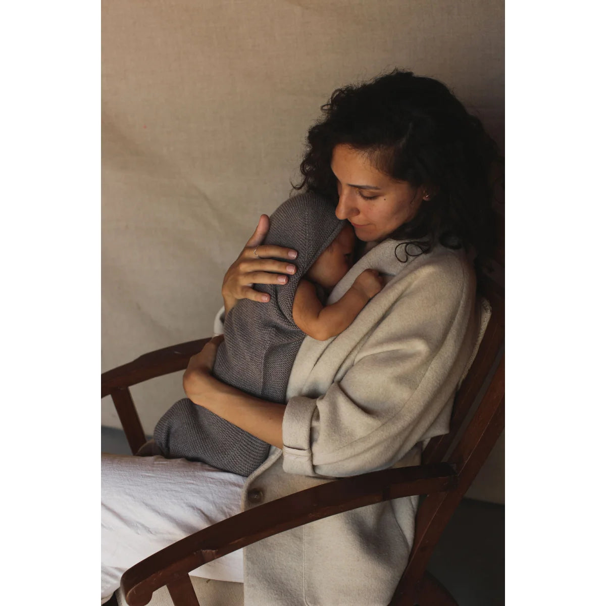 Frau umarmt Baby in einem Stuhl mit Cocoon Babydecke Otter im Hintergrund