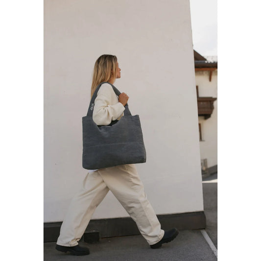 Frau trägt eine dunkelgraue Wickeltasche mit zwei Schultergurten, Denim Diaper Bag Grey