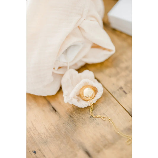 Zarte weiße Rose mit goldener Halskette auf Blütenblättern für Doudou Hase