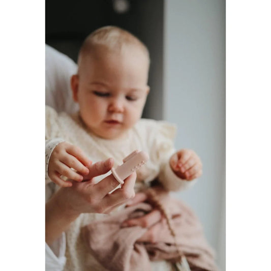 Baby in weißem Outfit mit kleiner Zahnbürste aus dem Produkt Finger Zahnbürste