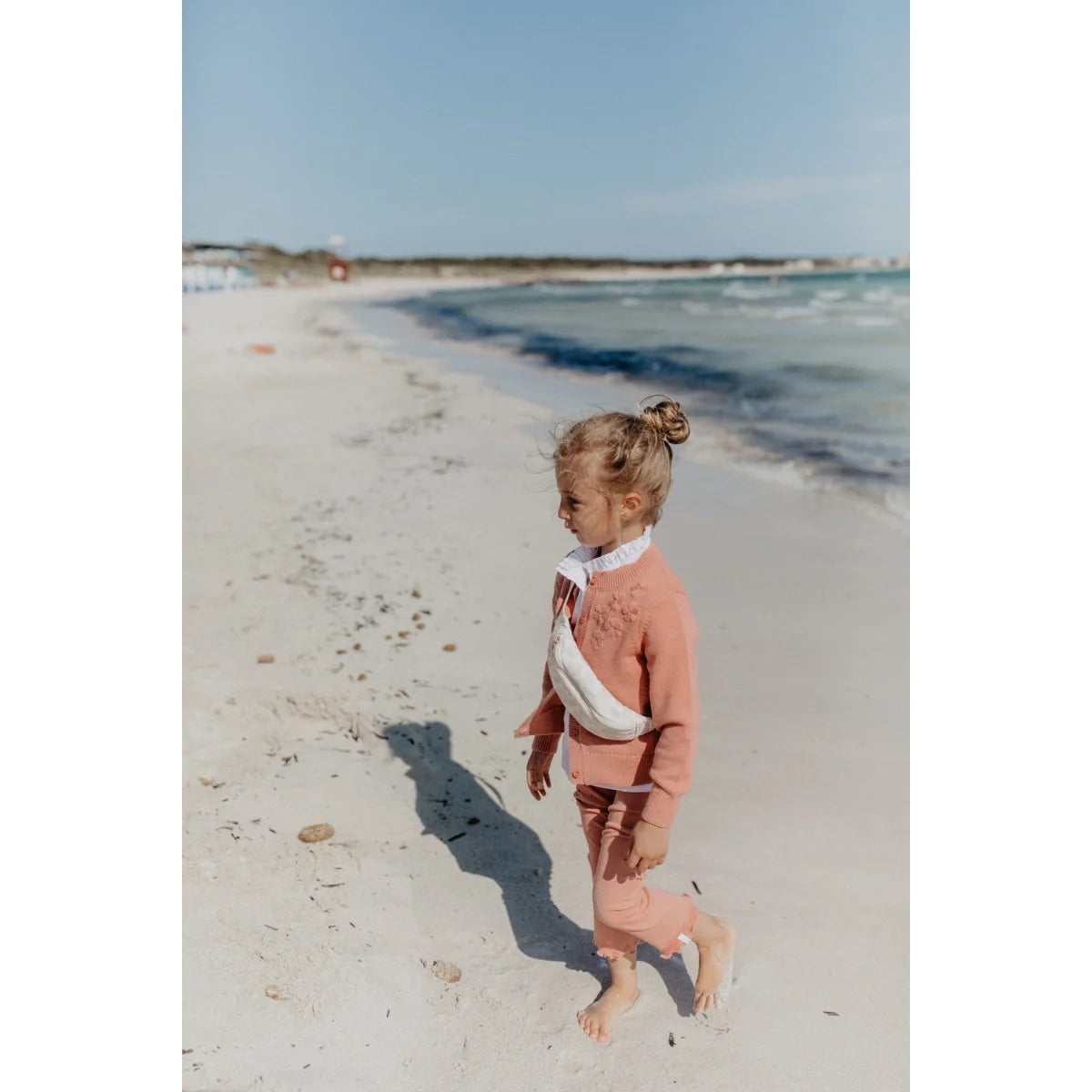 Weiches Kind in Strickpullover und nachhaltiger Babykleidung mit Zierkordel vorn