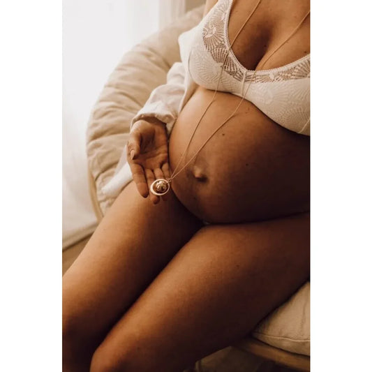 Schwangere Frau mit Ring berührt ihren Bauch, GAÏA Schwangerschaftsbola in Roségold