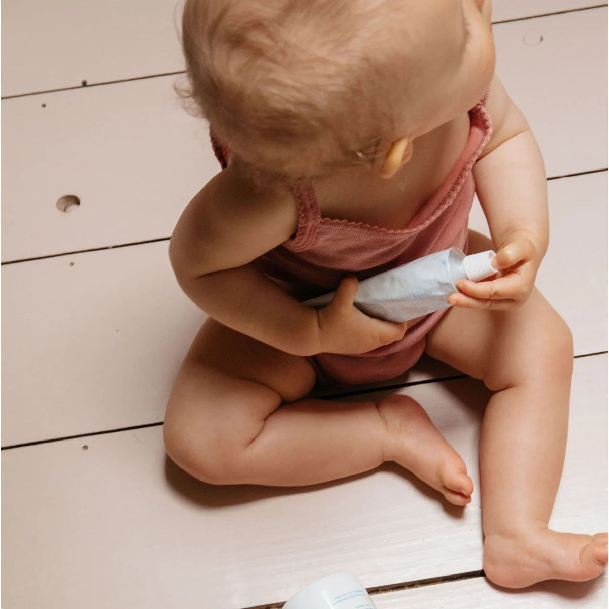 Baby hält eine Tube Lotion für sanfte Hautpflege im Produkt Gentle Cream 100ml