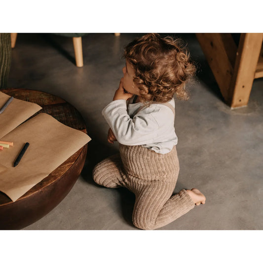 Kleinkind mit lockigen Haaren in weißem Oberteil und Strumpfhosen von Peanut Blend