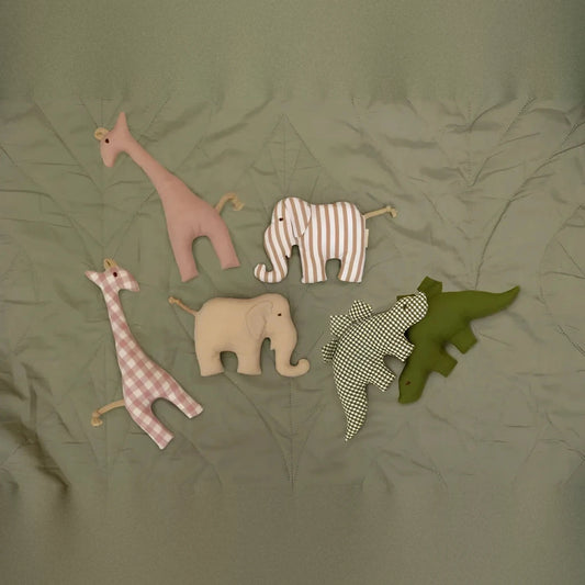Senger Naturwelt Grasping Toy Dino in green next to other grasping toys on green fabric