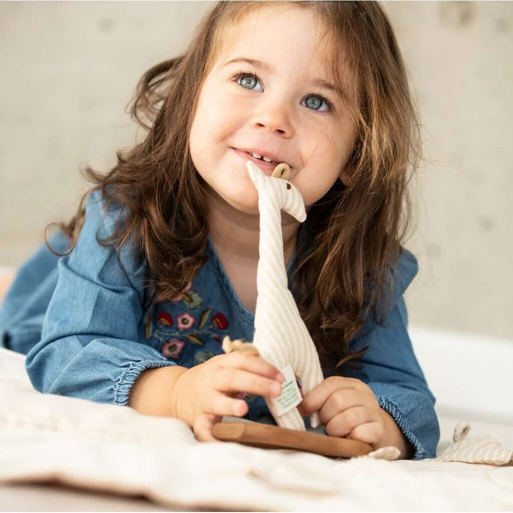 Lächelndes Kind hält ein Plüschtier Giraffe vom Produkt Greiftier Giraffe