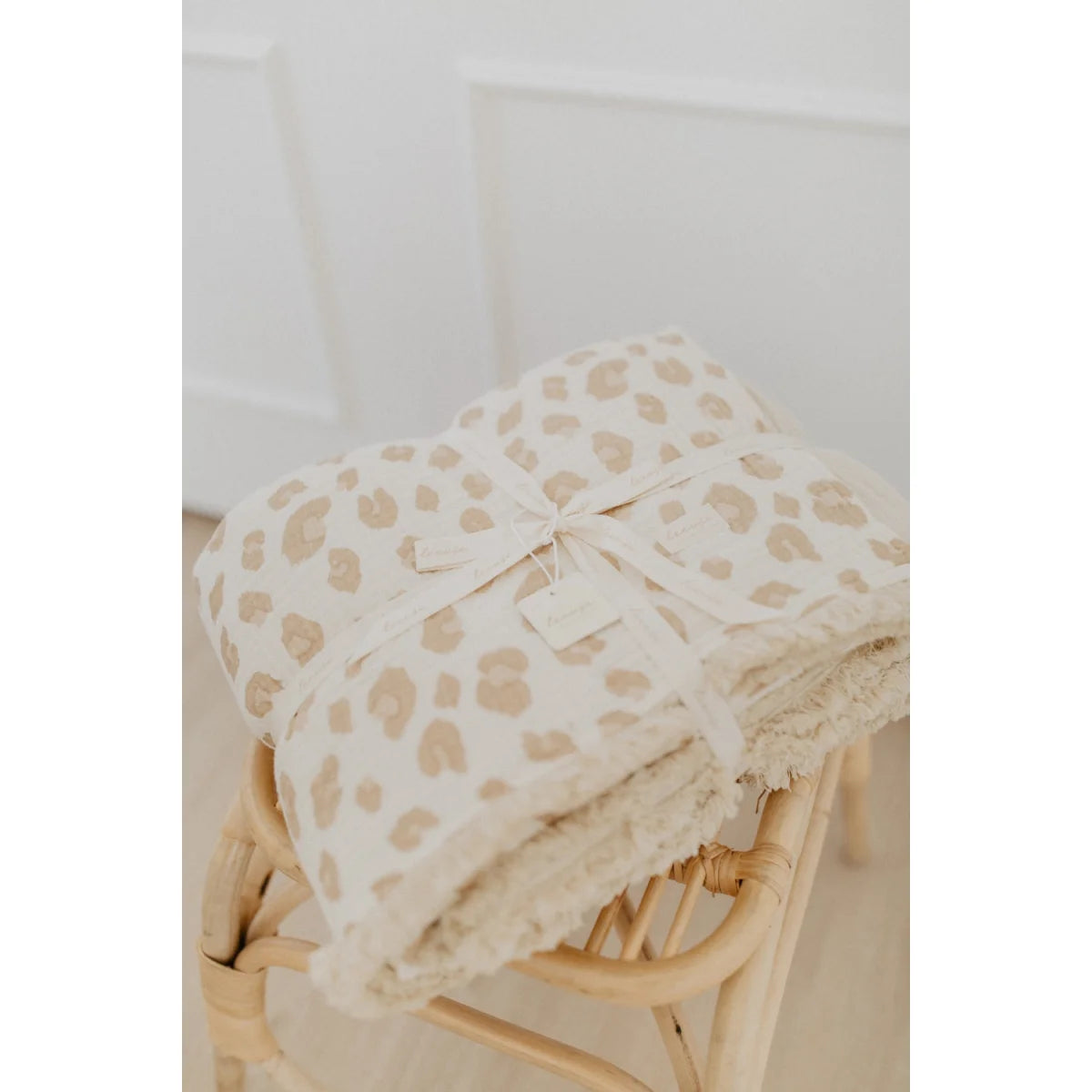 Gefaltete Tagesdecke mit Leoprint und cremefarbenem Band, passend zum Produkt Grosse Tagesdecke zum Wenden leoprint cappuccino