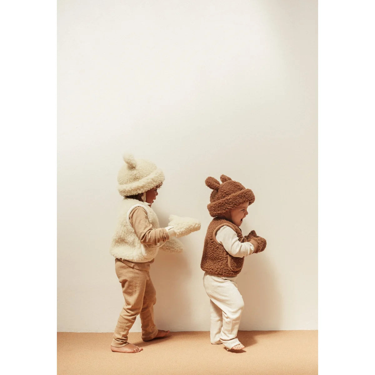 Zwei Kleinkinder in gemütlichen Winteroutfits mit tierischen Mützen und Westen