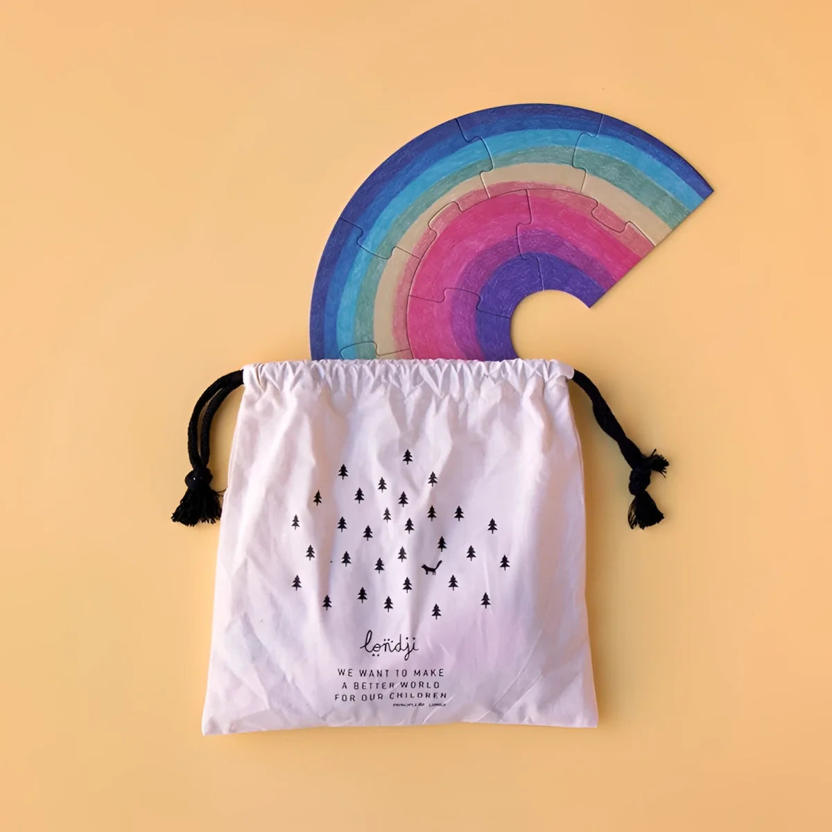Bunte Holzpuzzle in Regenbogenform aus einem weißen Baumwollsack mit Baum-Muster
