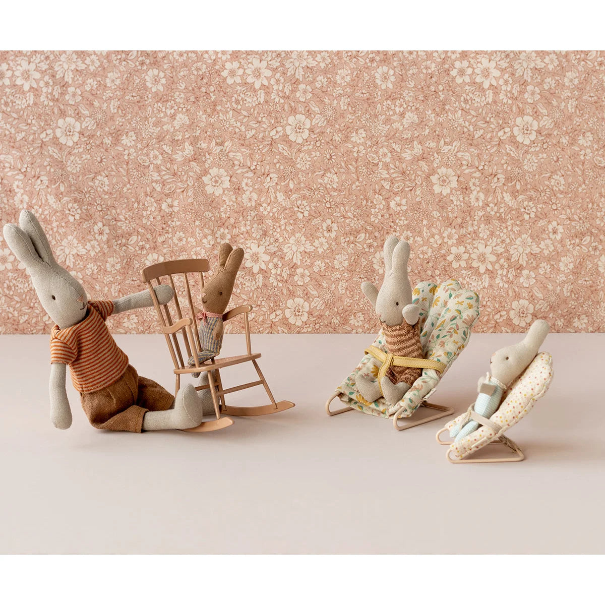 Gestopfte Hasen mit T-Shirt und Shorts neben einem_minimalistischen Schaukelstuhl