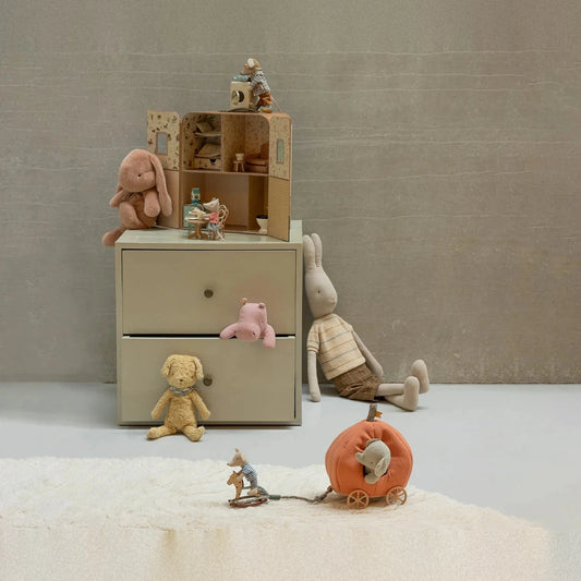 Maileg plush rabbit medium in Vintage rose on a chest of drawers, scene with a doll's house and soft toys