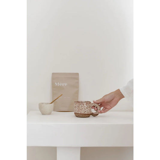 Hand hält schimmernde Tasse mit Himbeerblättertee und Glitzer