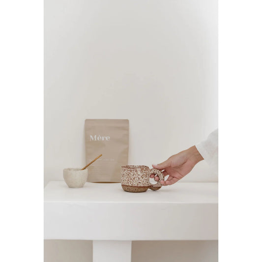 Hand hält schimmernde Tasse mit Himbeerblättertee und Glitzer