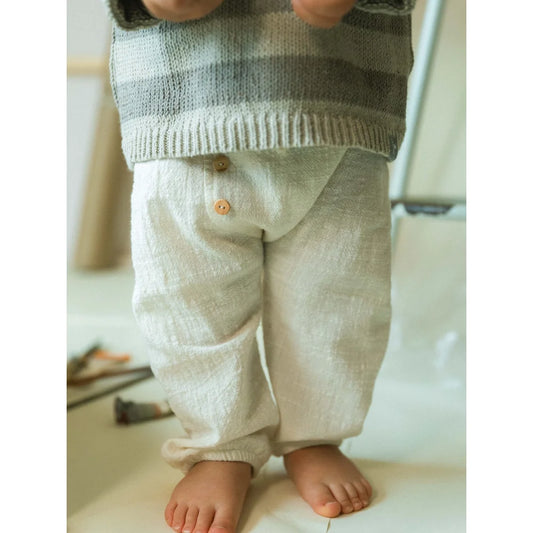 Kind in Leinenhose aus Bio-Baumwoll-Musselin, natürliche ungefärbte Farbe