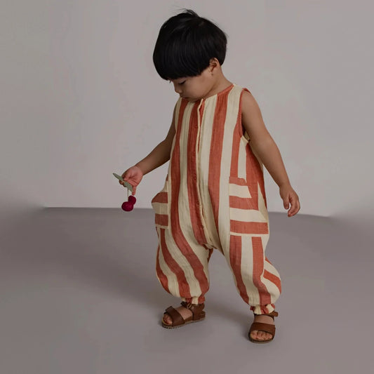 Kind trägt ärmellosen Organic Zoo Jumpsuit in Tomato Stripes mit aufgesetzten Taschen