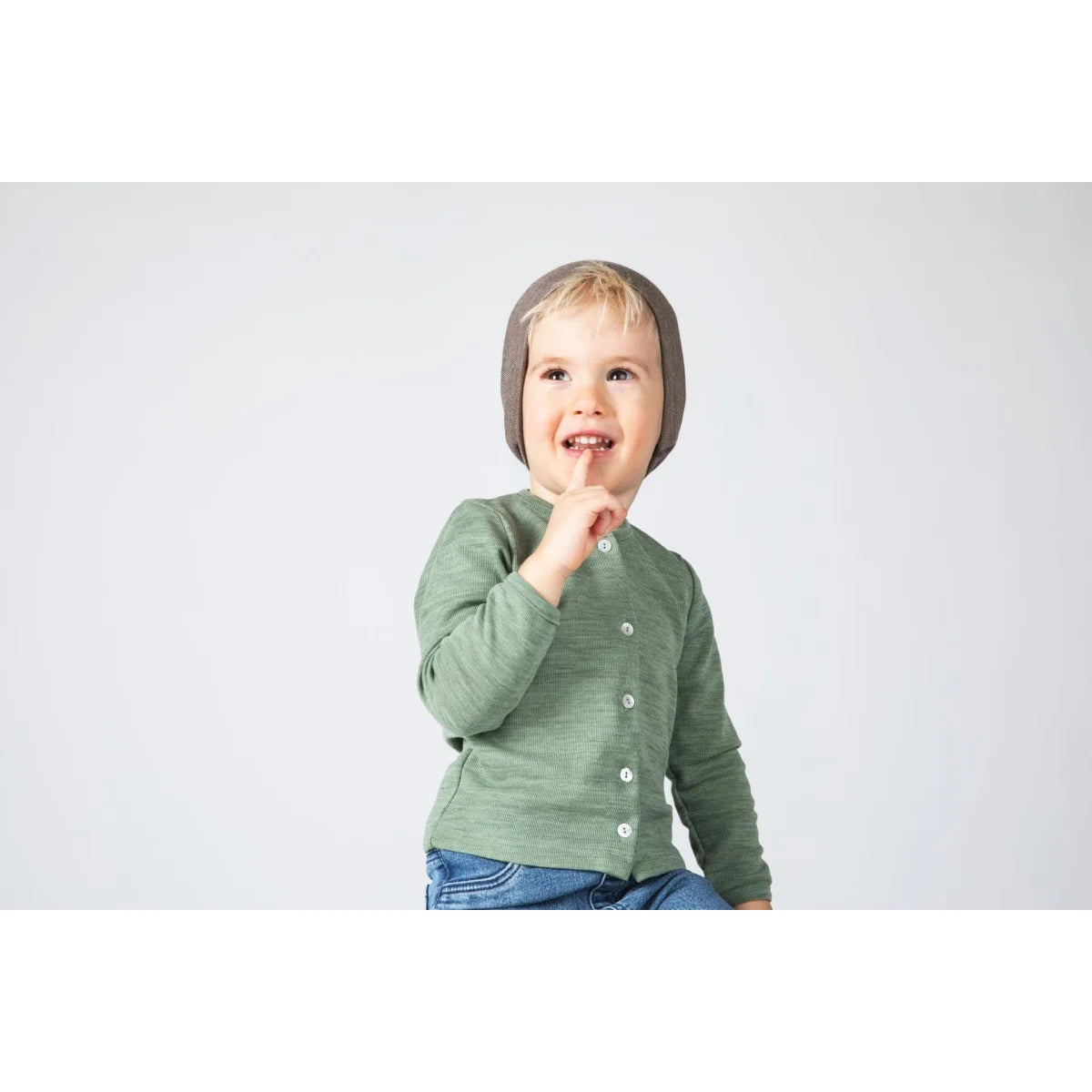 Kleines Kind in weicher grauer Strickmütze und grüner Nuss-Kinderjacke