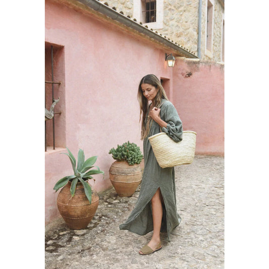Frau in langem grünen Kleid mit Strohtasche für das Produkt Kleid Bonita | Fern