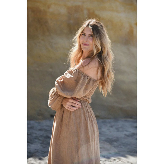 Frau mit langem blonden Haar in off-shoulder beigem Kleid ’Deia’ von Rye