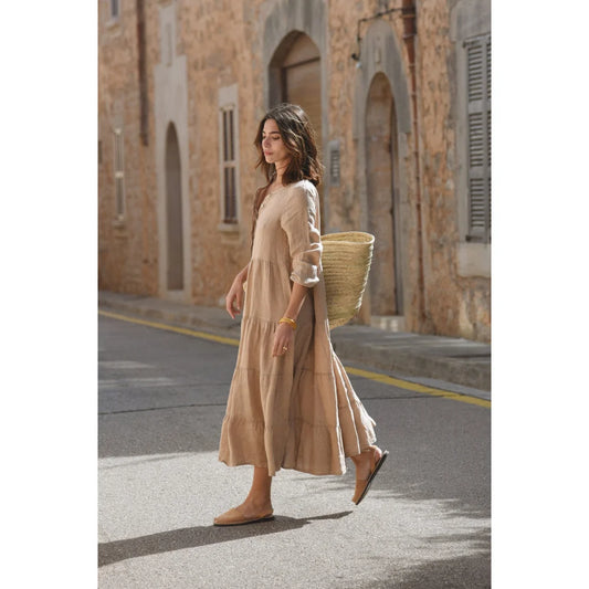 Frau im langen beigen Kleid Mara mit einem geflochtenen Korb in der Hand