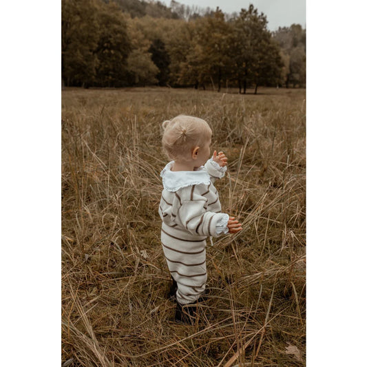 Kleinkind in gestreiftem Outfit steht im hohen Gras, Knit Pants Stripe | Coffee