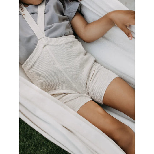 Cremefarbener Strick-Overall mit Trägern, getragen von einem Kind, Kurze Strumpfhose mit Träger