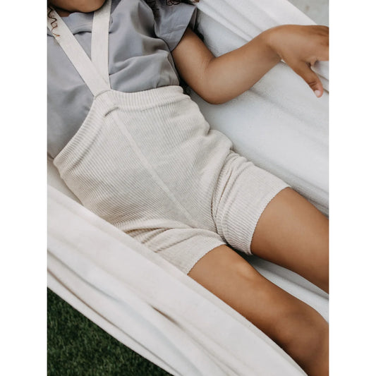 Cremefarbener Strick-Overall mit Trägern, getragen von einem Kind, Kurze Strumpfhose mit Träger