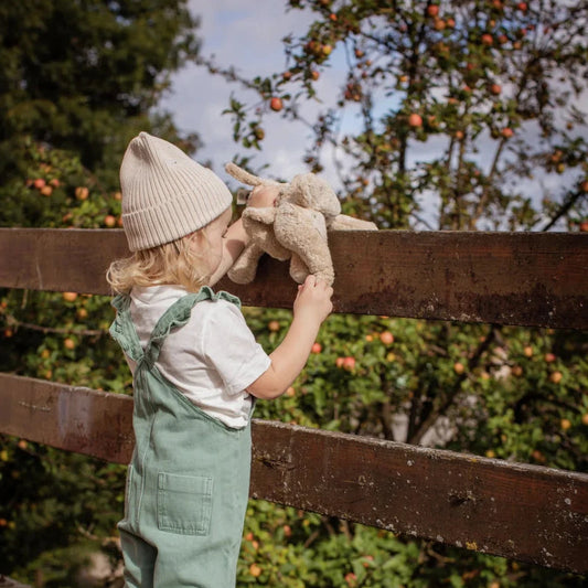 Child in dungarees holding Senger Naturwelt Small Plush Elephant in Leinen at a wooden fence
