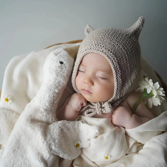 Sleeping baby in a knitted hat with the Senger Naturwelt Cuddly Toy Goose Small in White