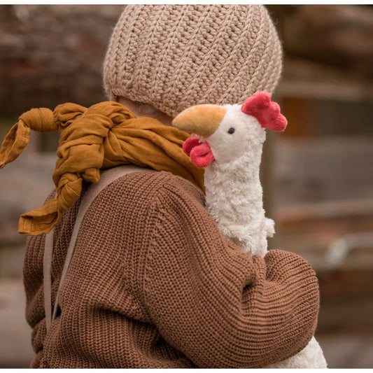 Plüsch weißes Huhn Spielzeug auf der Schulter einer Person im gestrickten Outfit