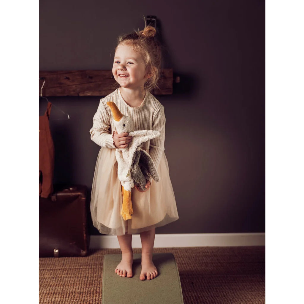 Junges Kind im cremefarbenen Kleid mit Kuscheltier Möwe klein in der Hand