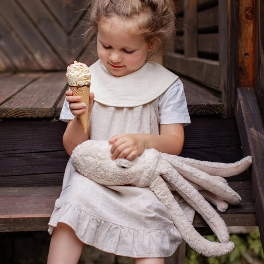 Girl in a light dress with vanilla ice cream and the Senger Naturwelt Small Octopus Plush Toy in Powder