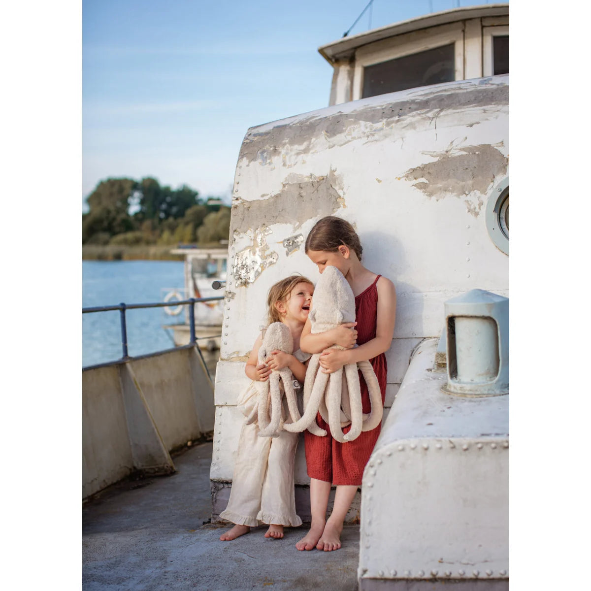 Zwei Kinder halten kleines puderfarbenes Kuschelotopus Toy