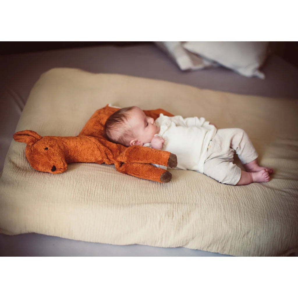 Schlafendes Baby kuschelt mit orangefarbenem Stofftier Kuscheltier Reh klein